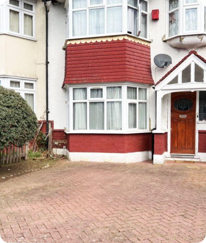 a house front with pavement which has all the excess grass previously growing out of it removed